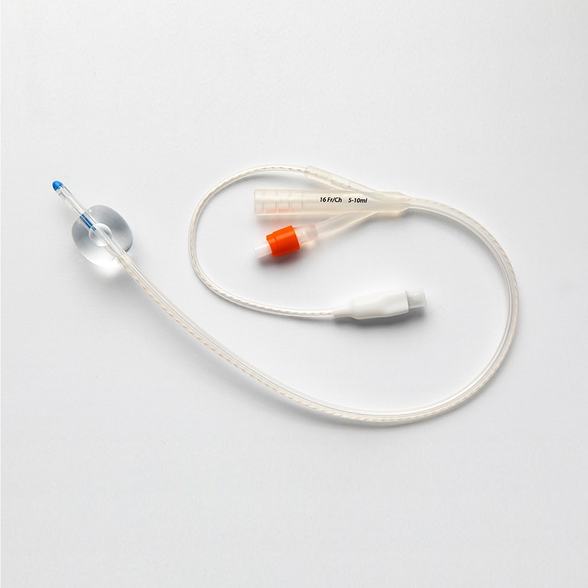 En urinkateter av plast med ballong och flera kopplingar, ligger på en vit yta.