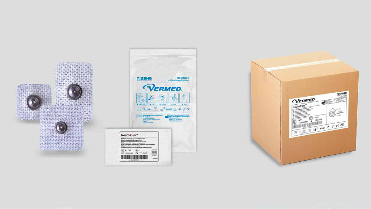 Tre medicinska elektroder, en plastpåse och en kartong med etikett på en grå bakgrund.