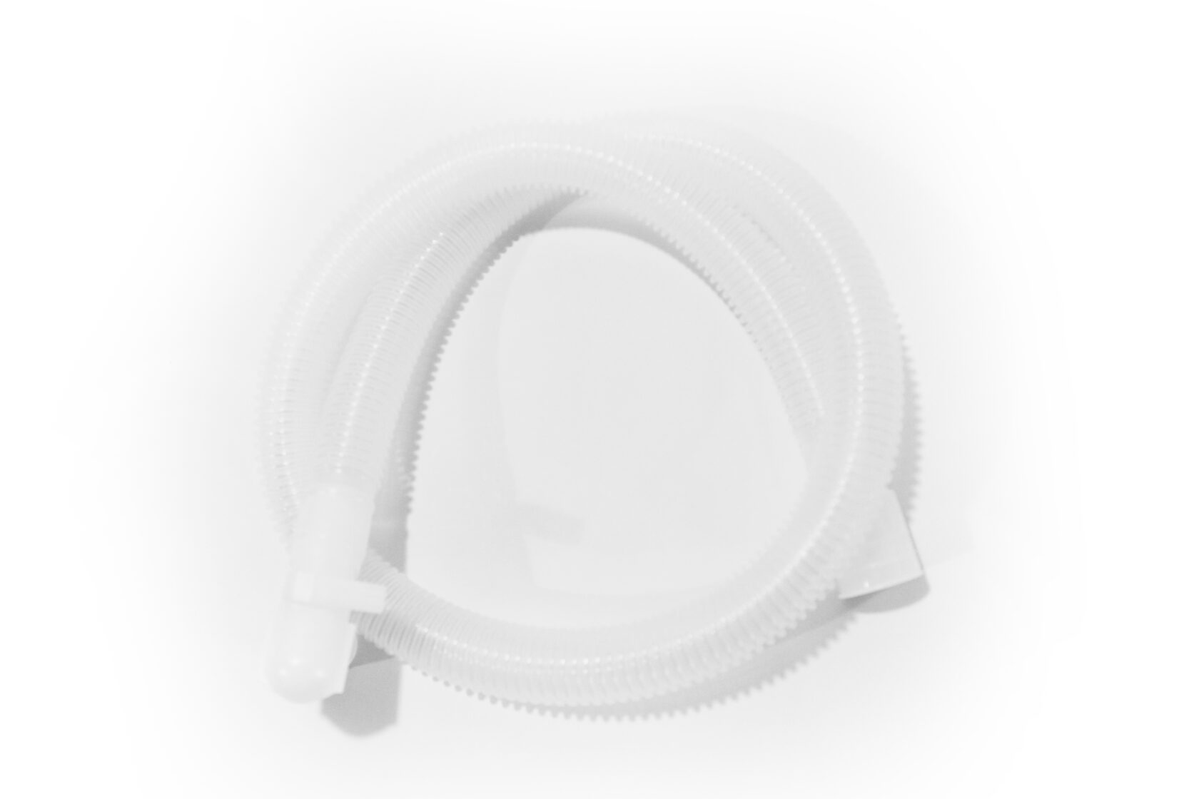 Virad genomskinlig korrugerad plastslang med kopplingar i båda ändar, placerad på en vit yta.