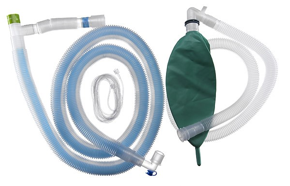 Medicinskt andningskretsset med veckade slangar och en grön reservoarpåse på vit bakgrund.