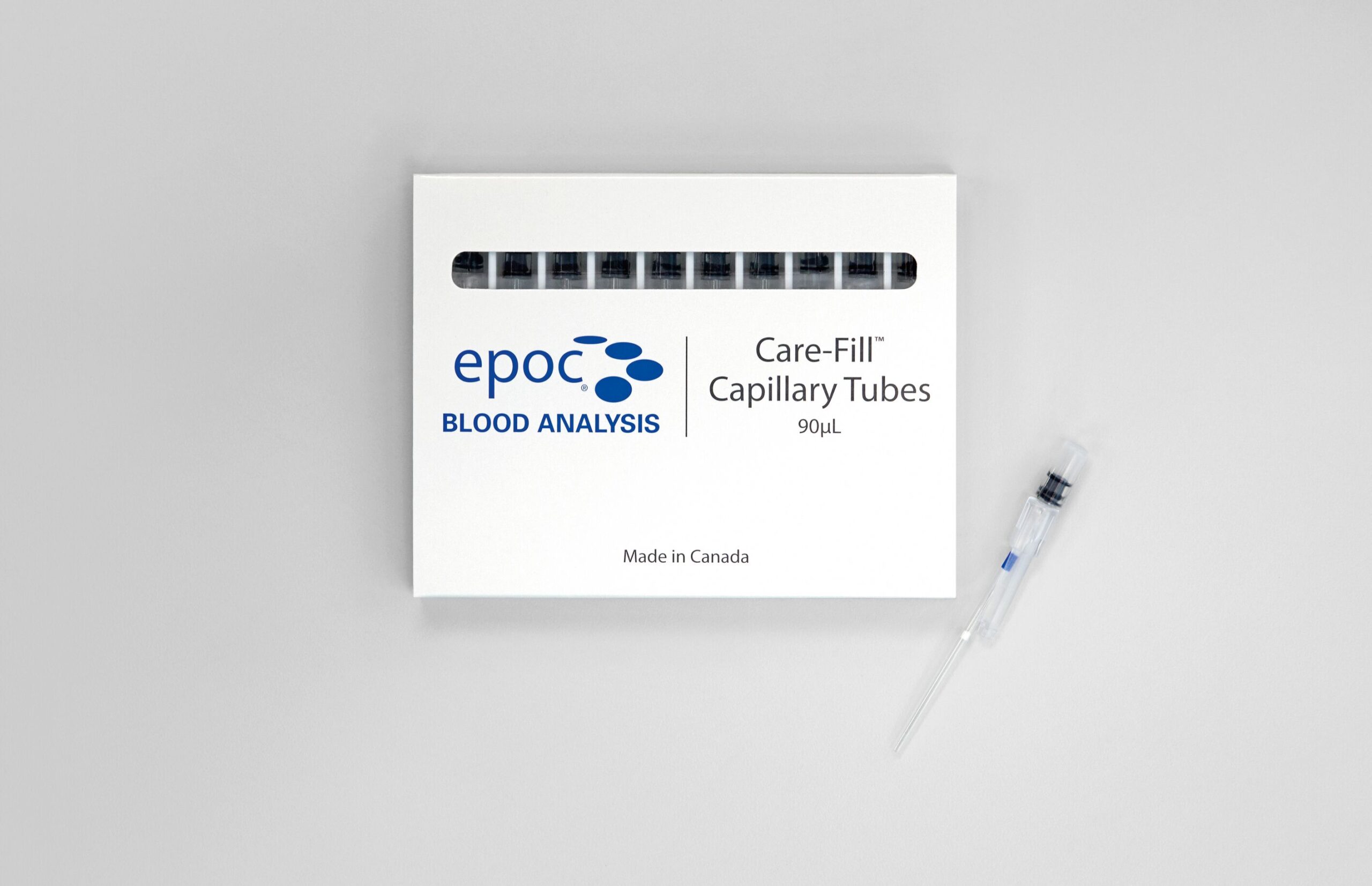 Vit låda märkt "epoc BLOOD ANALYSIS Care-Fill Capillary Tubes 90µL", med en kapillärtub bredvid på bordet.