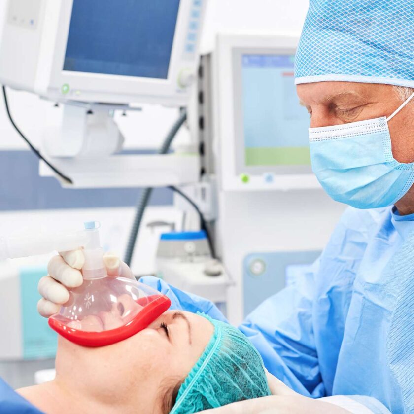 Patient som sover med anestesimask och anestesispecialist