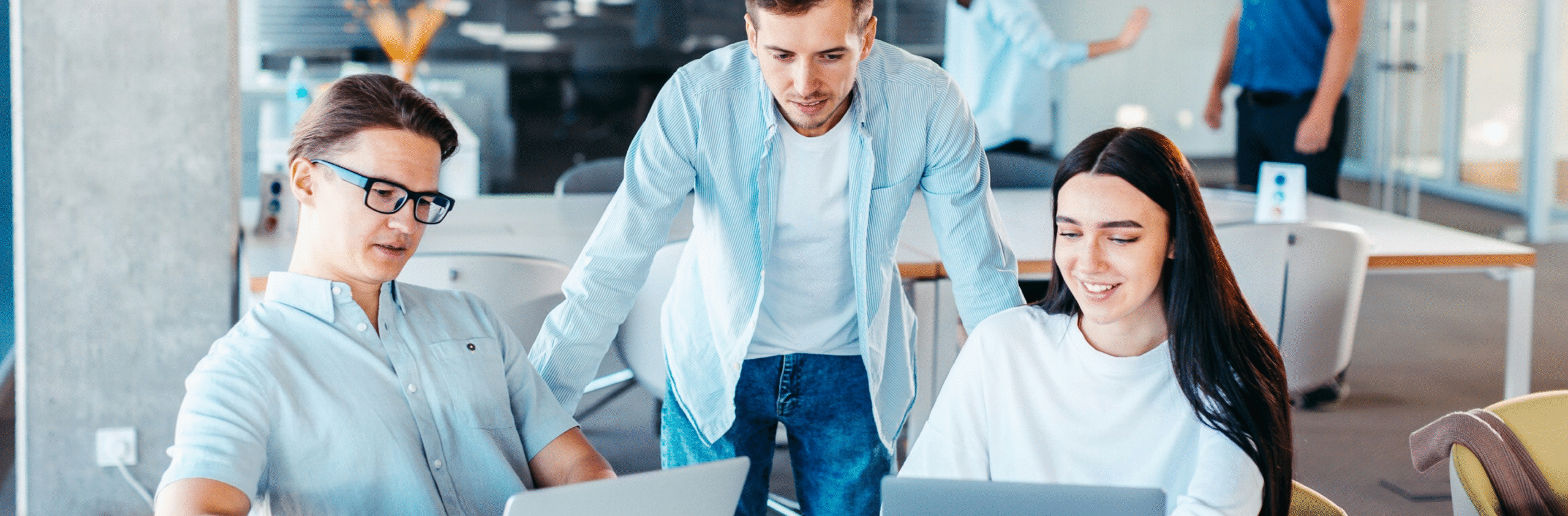 Tre unga yrkesverksamma samarbetar vid bärbara datorer i en modern kontorslokal.