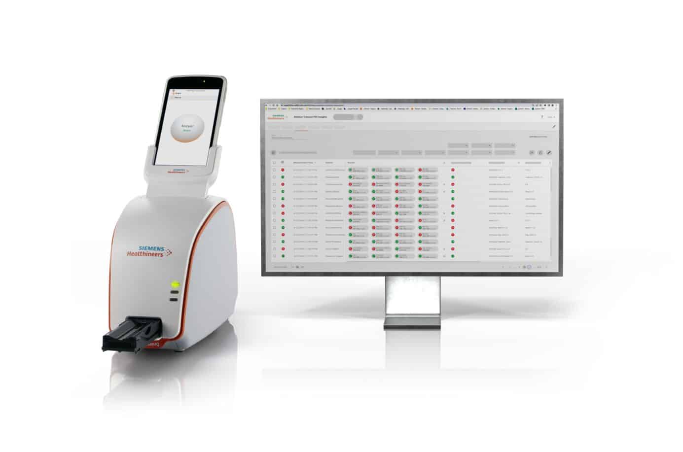 Medicinsk analysator med Siemens Healthineers-märkning bredvid en datorskärm som visar analysresultat.